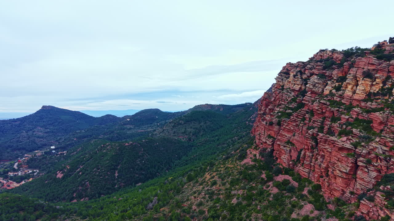 Vista panoramica di formazioni rocciose rosse e montagne in un paesaggio naturale con un cielo nuvoloso durante il giorno.