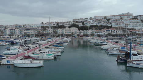 drone-captures-a-tracking-shot-passing-rows-of-yachts-docked-near-coastal-town