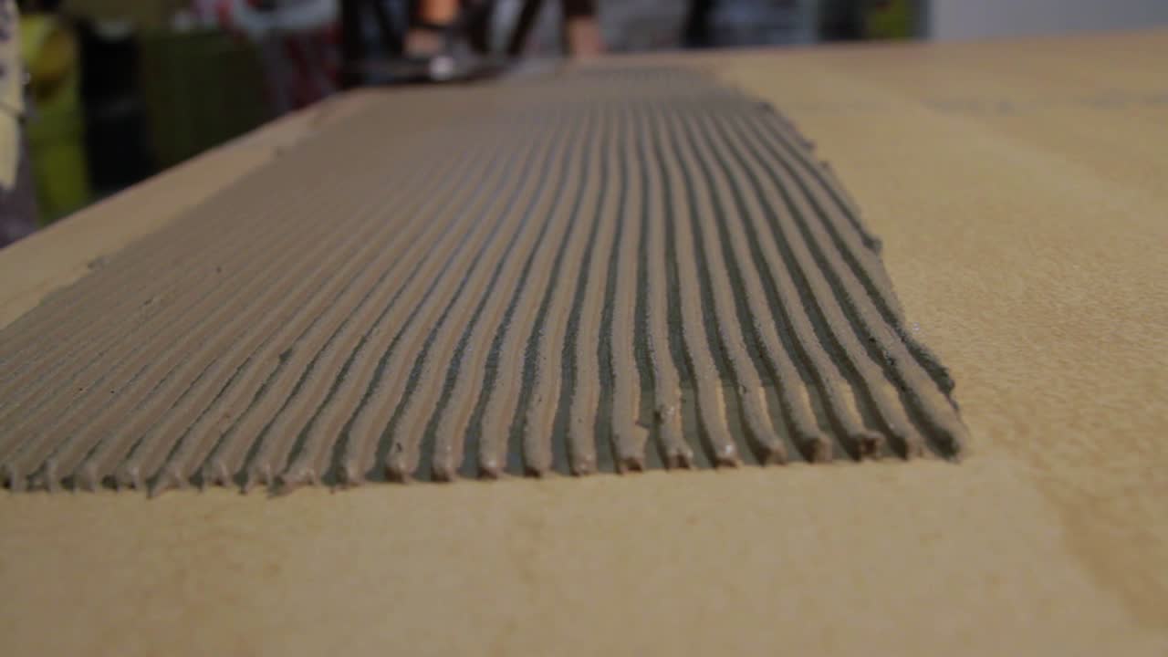 Worker puts tile glue on the floor