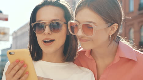 two women friends looking at a phone in the city