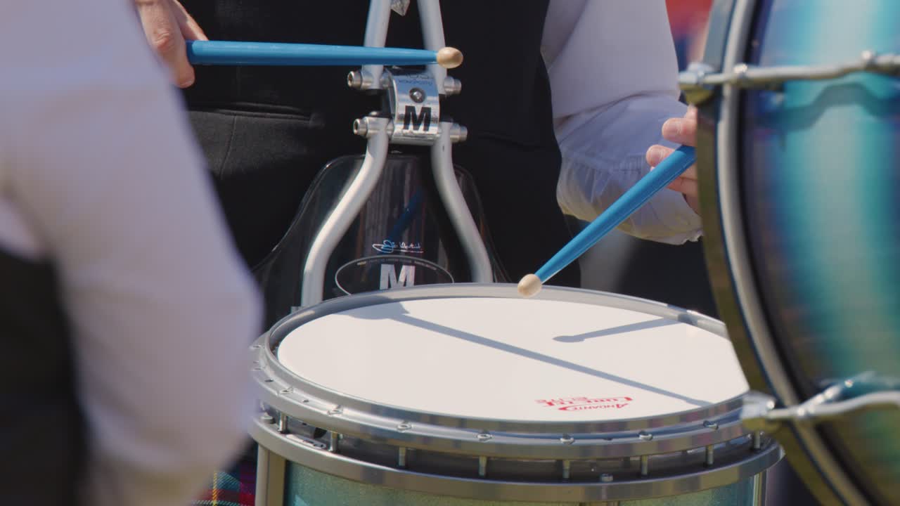 Close-up of drummer in traditional Scottish attire playing snare drum at outdoor Edinburgh event