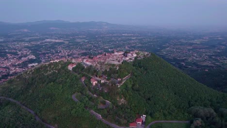 Aerial-toward-castle-ruin-overlooking-the-small-town-on-mountaintop