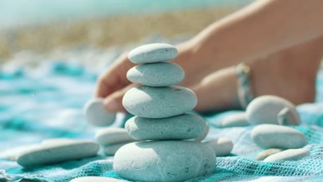 child hand building pebbles tower on seaside. pile of balanced round stones