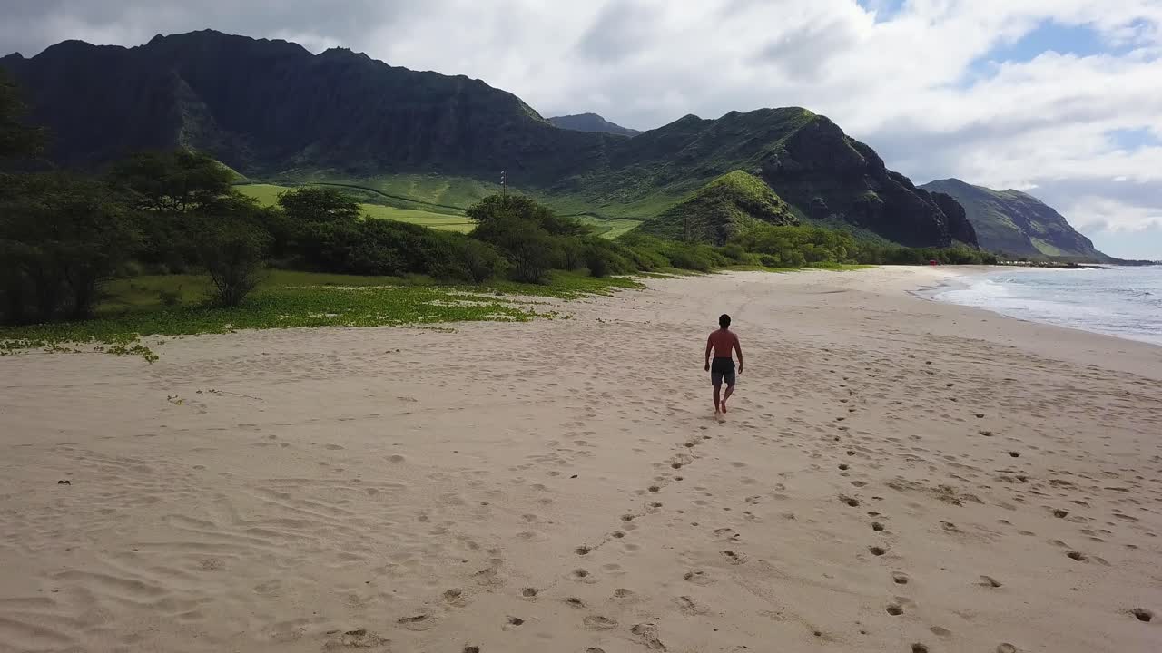 hombre atlético solitario camina por la playa tropical con montañas iluminadas por el sol