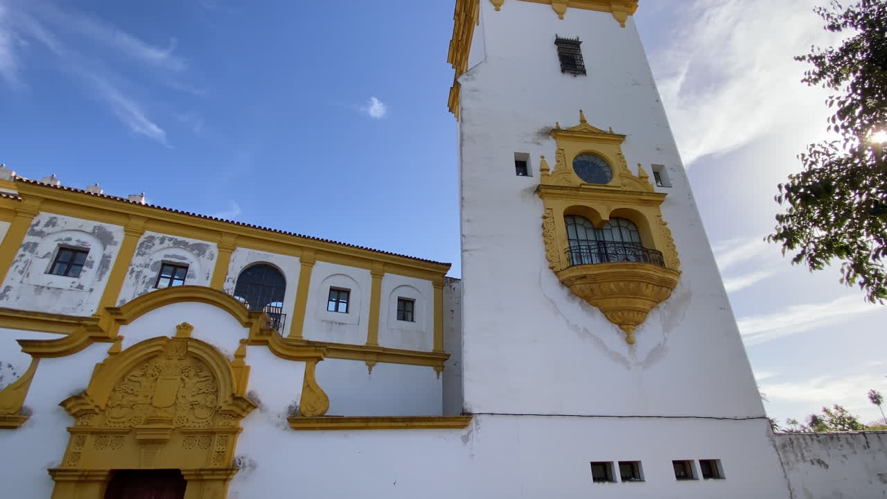 Seville'de uzun kulesi ve süslü balkonu olan bir barok kilise cephesi, masmavi bir gökyüzüne karşı yükseliyor