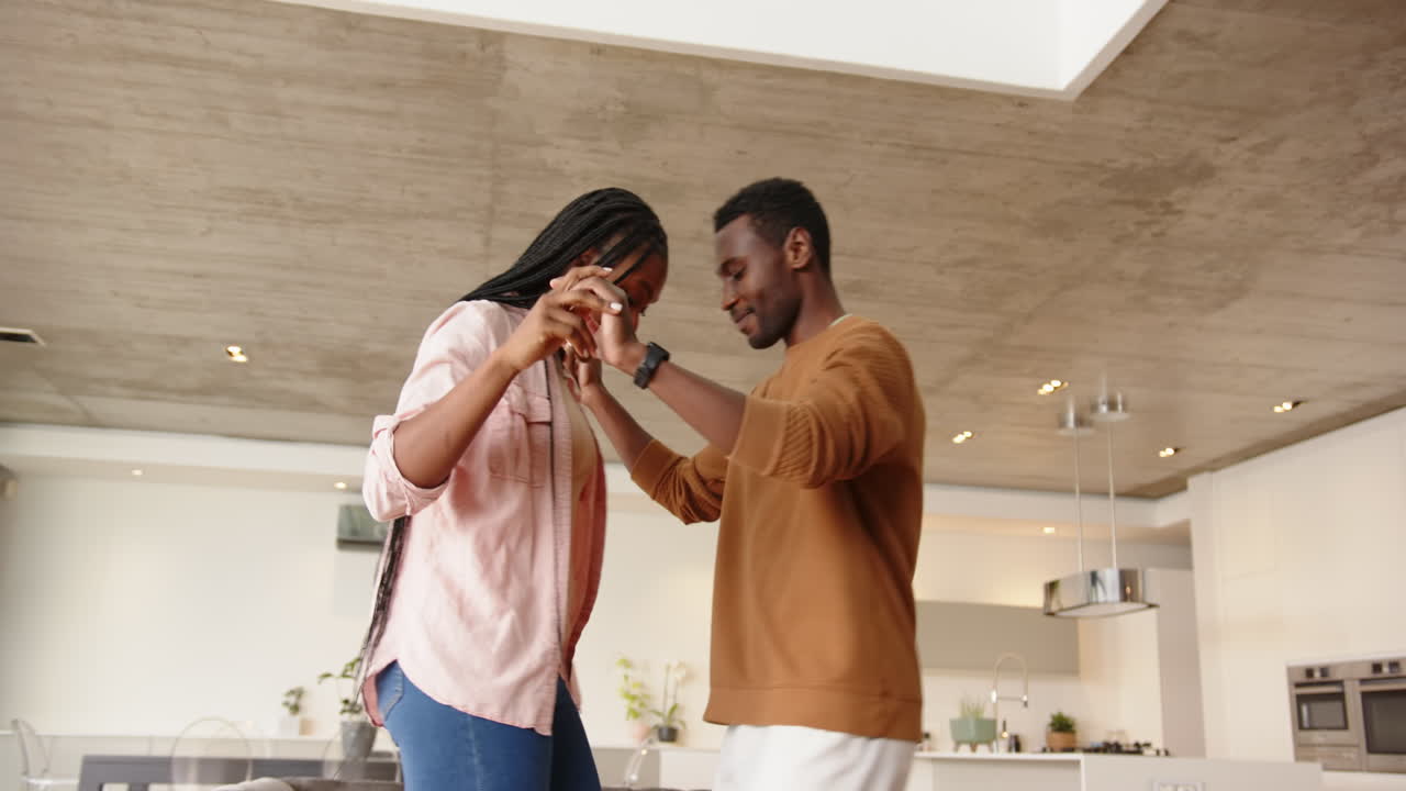 Dancing together, young african american couple enjoying time at home in modern living room