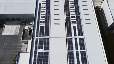 Solar-panels-on-roof,-dolly-out-to-a-rural-landscape-with-green-hills,-crops,-and-blue-sky