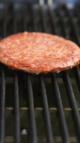 raw hamburger patty on a grill