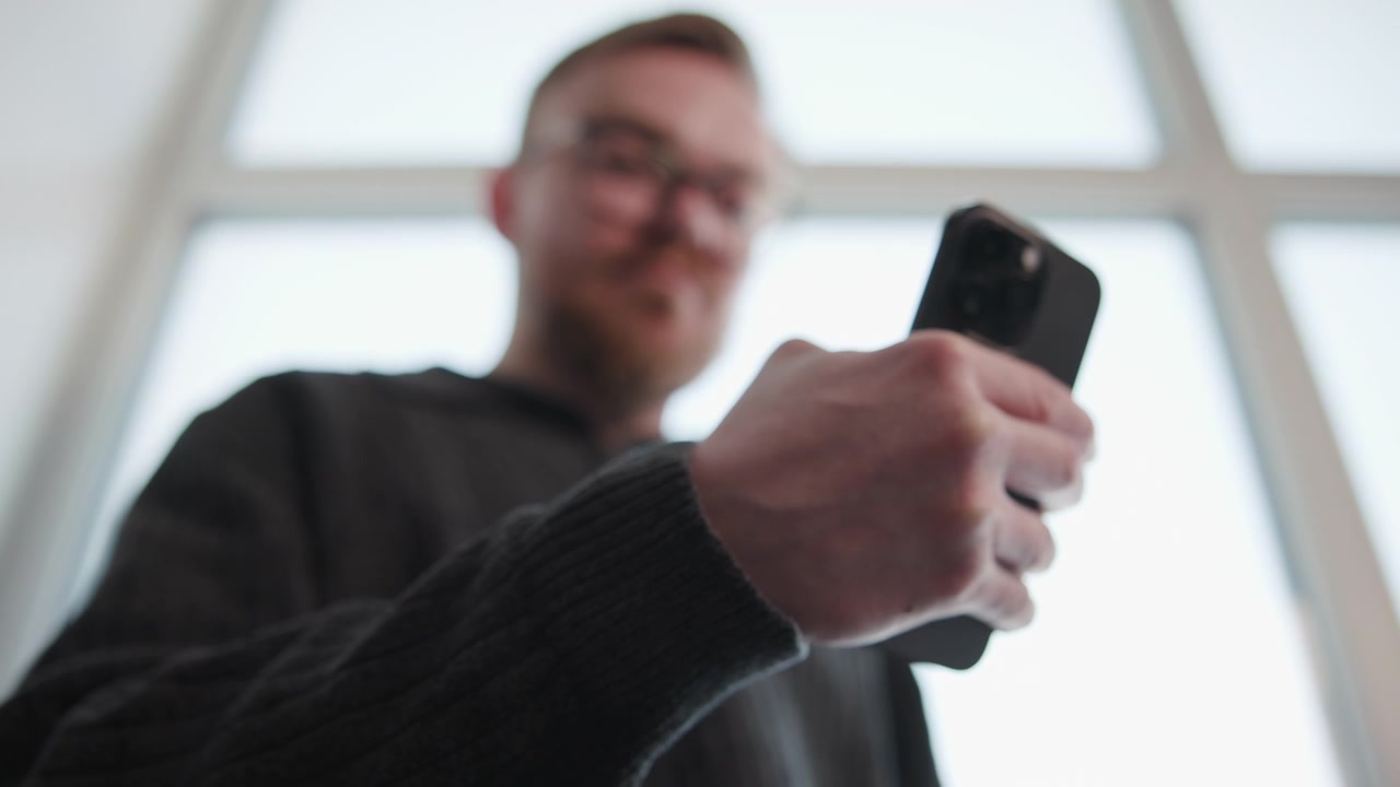 White Man Inspecting Phone Camera Near Window, Low Perspective Closeup On Device And Hand, Testing Image