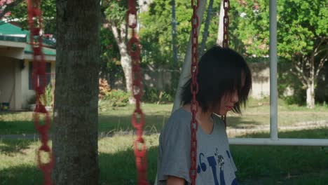joven sombría sentada en un columpio con la cabeza hacia abajo