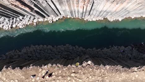 elevándose por encima de la persona que camina sobre columnas hexagonales de basalto en la parte inferior del cañón studlagil en el este de islandia