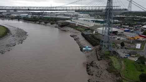 Historic-industrial-Newport-transporter-bridge-platform-connection-moving-over-river-Usk-aerial-pull-back