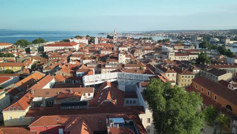 Drone-lift-up-over-Zadar-peninsula,-old-town-red-rooftops,-tip-of-the-Captains-tower-and-view-to-church-St