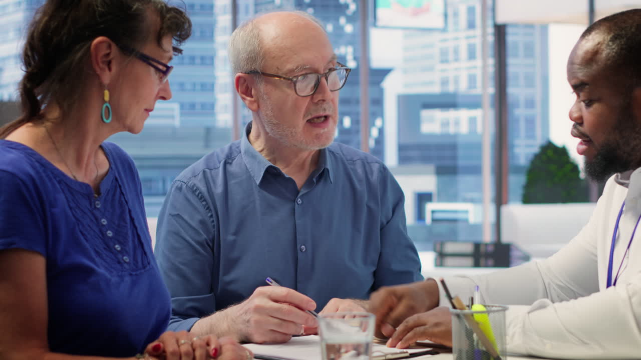 노인들이 브로커와 함께 은퇴 계획 계약 조건을 읽습니다.