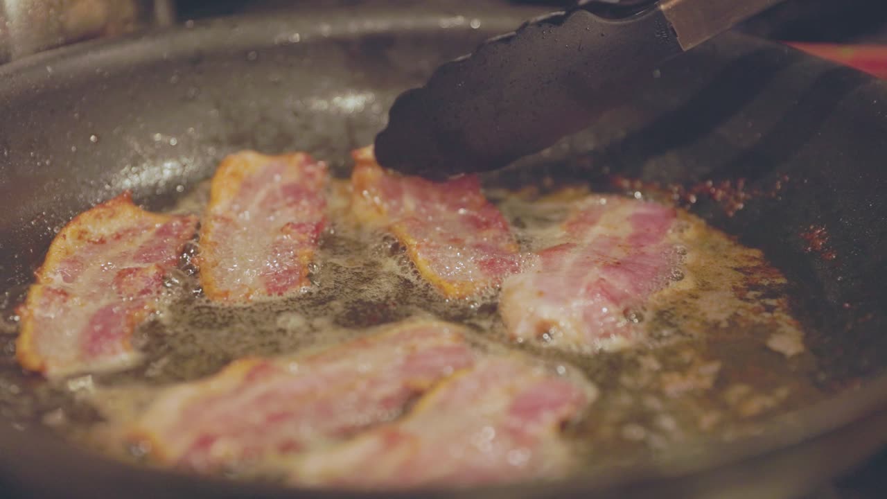Flipping Bacon Sizzling In Pan While Cooking