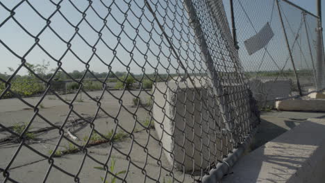 una vieja valla de tela metálica oxidada bloquea la entrada a un lote industrial abandonado que quedó de los días de fabricación de gm en flint, michigan