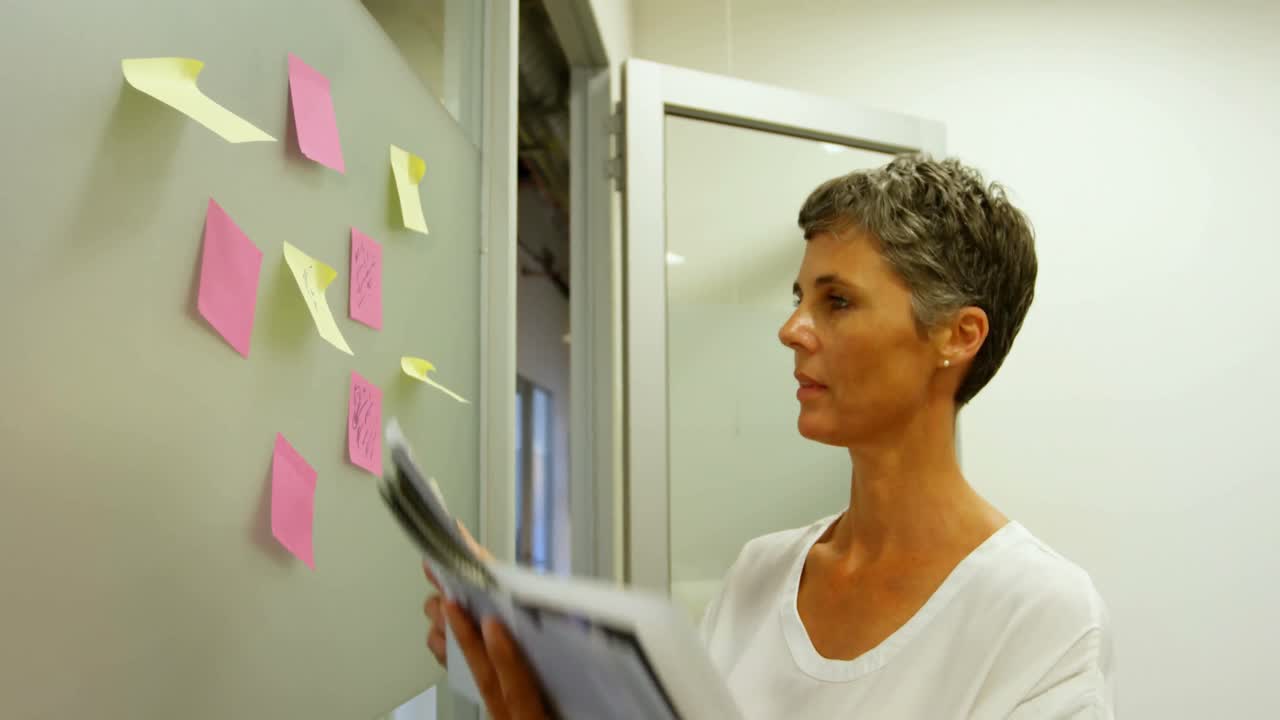 Businesswoman checking textile samples while looking at sticky notes 4k