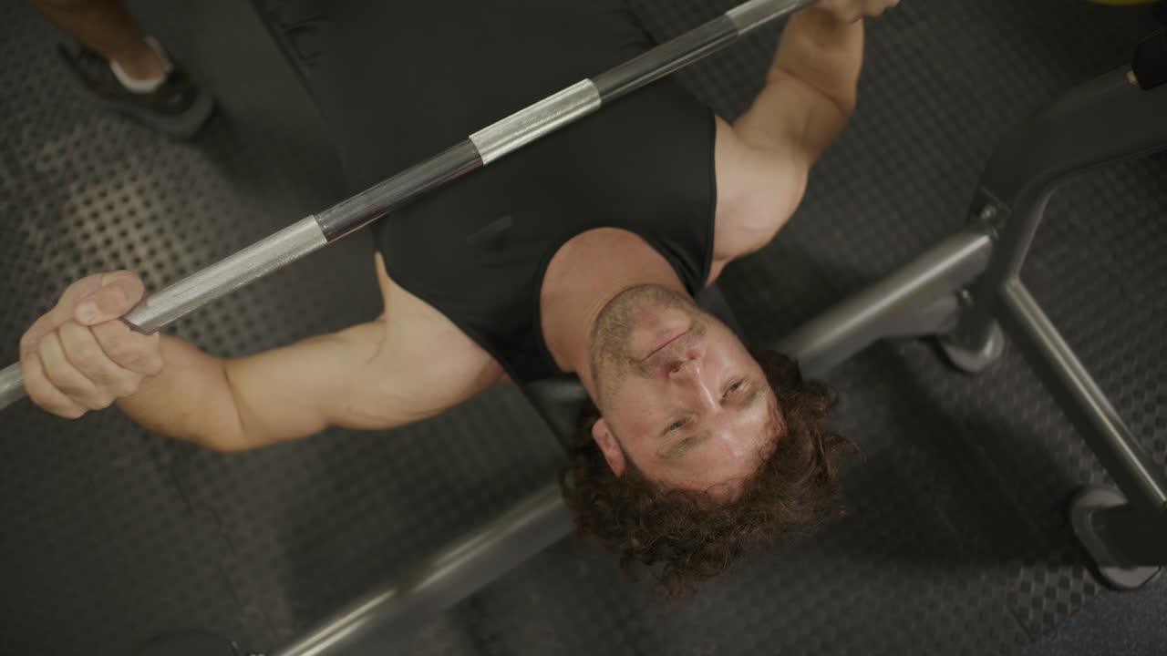 Overhead Shot of Man Lifting Barbell During Bench Press Exercise in Gym