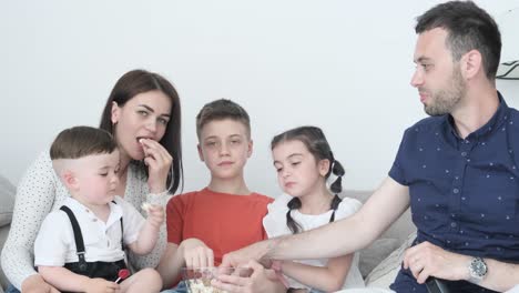 family enjoying time together watching tv and eating popcorn