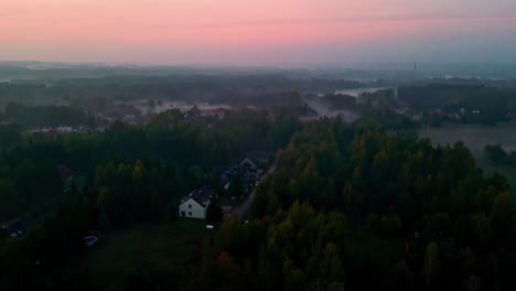 Aerial-view-of-colorful-sky-illuminated-by-sunset-over-large-villa's-surrended-by-forest