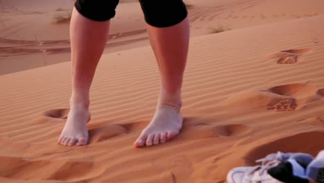 Close-up-shot-of-woman-walking-up-the-sand-desert-dune-without-shoes