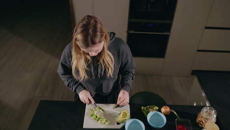 woman chopping avocado in kitchen