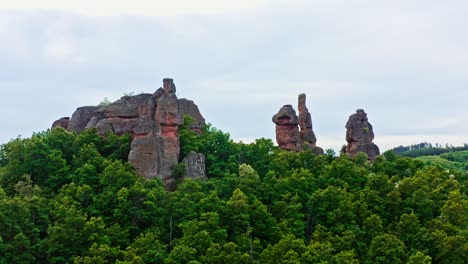 Belogradchik-sandstone-rock-formations-rise-above-Bulgarian-forest-landscape,-drone-shot