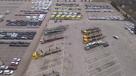An aerial video of a car depot showcasing rows of parked cars, vans, and yellow commercial vehicles.