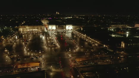 Aerial-view-of-Place-de-la-Concorde-with-Luxor-Obelisk.-Vehicles-passing-illuminated-square-in-late-evening.-Paris,-France