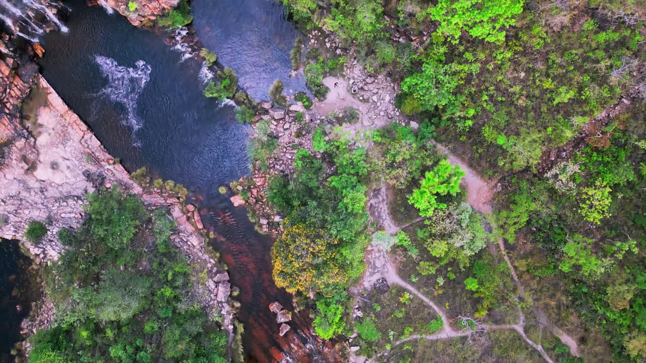 high altitude drone overhead view capturing dos Couros waterfall cascading through rocky terrain, surrounded by lush vegetation in the brazilian highlands of Chapada dos Veadeiros national park, Goias