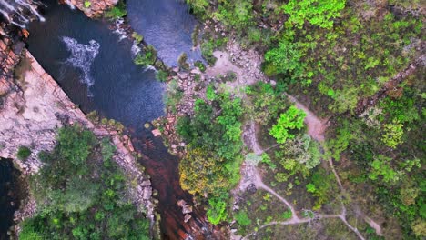 high altitude drone overhead view capturing dos couros waterfall cascading through rocky terrain, surrounded by lush vegetation in the brazilian highlands of chapada dos veadeiros national park, goias