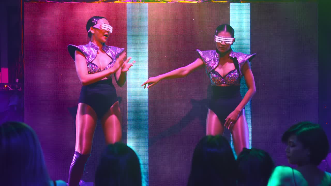 группа людей танцует в ночном клубе на дискотеке под ритм музыки ди-джея на сцене