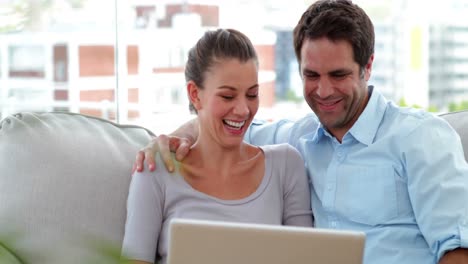 pareja relajándose en el sofá usando una computadora portátil