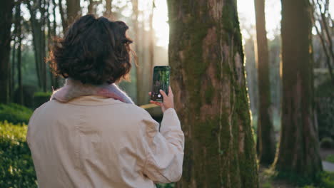 focused woman capturing forest using cellphone closeup. brunette taking picture