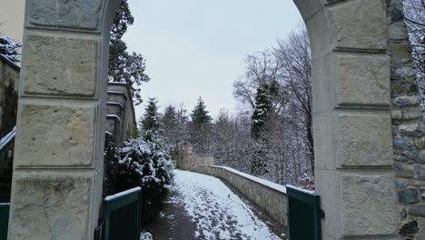 Drohne-Fliegt-Durch-Einen-Steinernen-Bogen-Und-Entlang-Eines-Weges-In-Einer-Winterlandschaft-In-Der-Schweiz