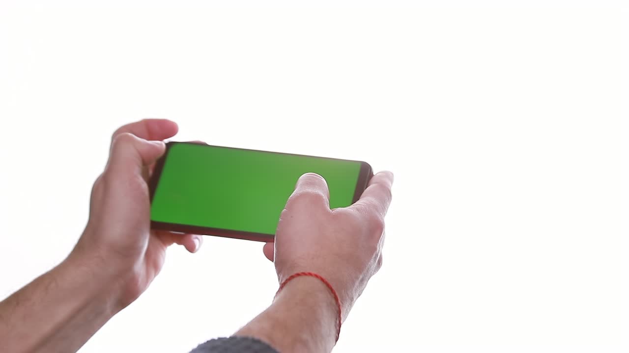 man's hand holding a smartphone with a vertical green screen
