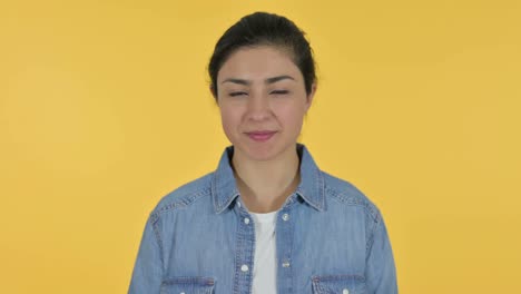 young indian woman with thumbs up, yellow background