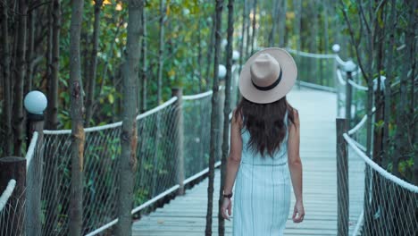 Unrecognizable-woman-seen-from-behind-while-walking-through-botanical-garden,-back-view-of-tourist