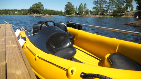 a small yellow powerboat tied to the pier on a lake from the front, medium shot