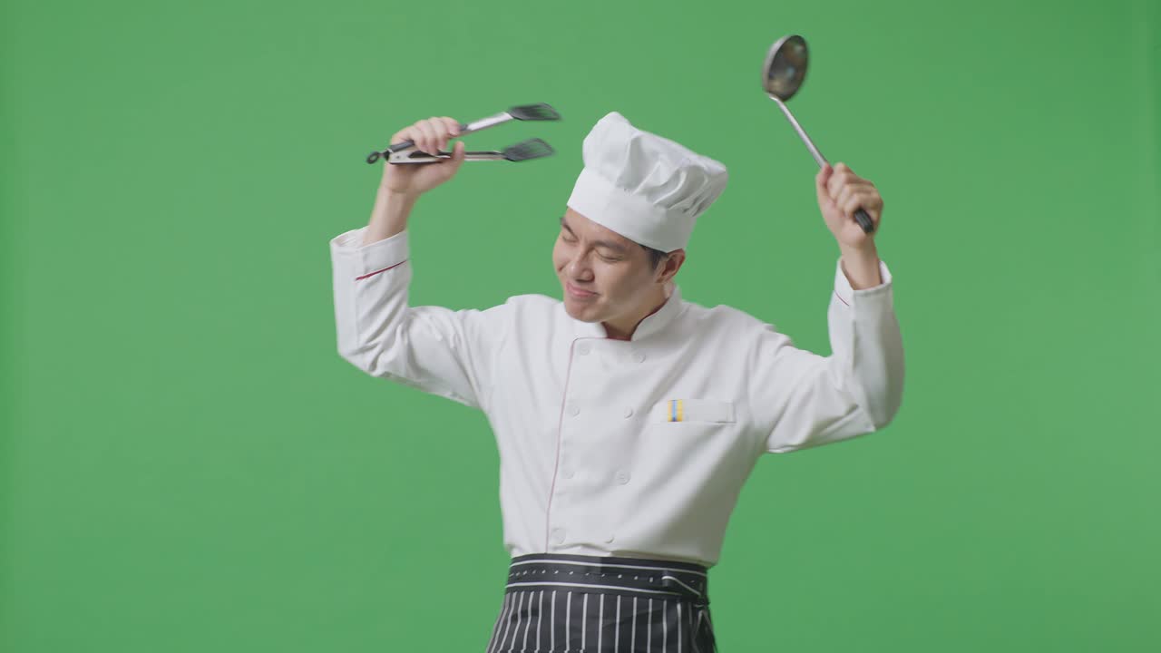 Asian Man Chef Holding Tongs And Ladle And Dancing While Standing In The Green Screen Background Studio