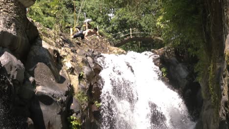 toma en cámara lenta de un acantilado turístico americano saltando y haciendo un ganador de un acantilado en un charco de agua en la cascada alingaling en bali, indonesia