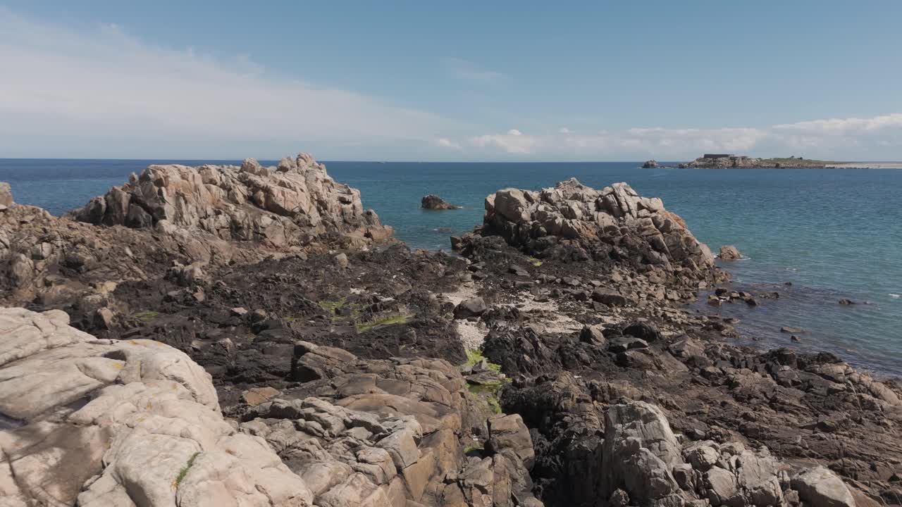 vuelo de avión no tripulado a marea baja sobre la costa rocosa con rocas y aves a la ensenada y vistas a través de la bahía en un día soleado y brillante en guernsey