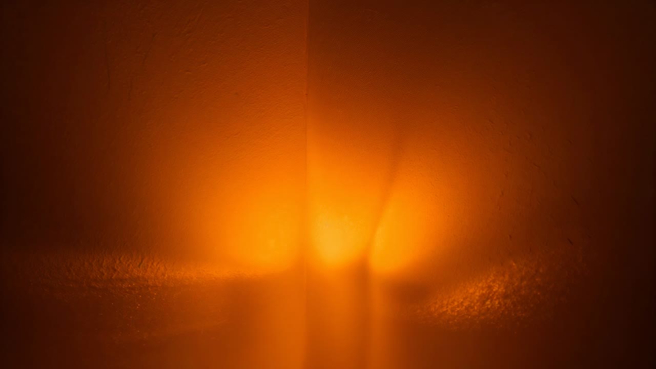 Flimmerndes, warmes Licht, dessen Kern sich über eine gefrostete Platte in einer Nahaufnahme verschiebt und Bänder und ein Dreieck bildet