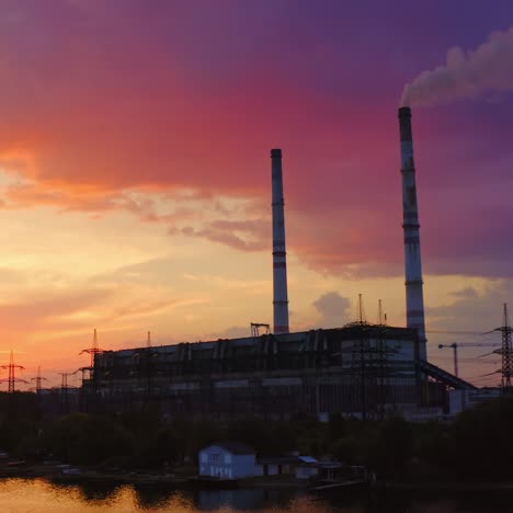 manufacturing at sunset. industrial factory near the river on the beautiful colorful background of the sky. chemical plant with smoke from pipe in the evening.