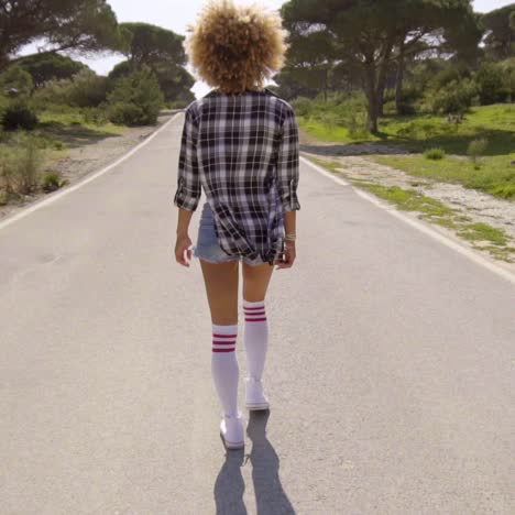 sexy young woman walking down a road at sunset