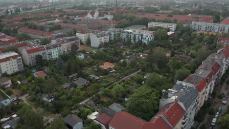 Aerial-view-of-family-houses-with-gardens-surrounded-by-multistorey-residential-buildings.-Backwards-reveal-of-city.-Berlin,-Germany