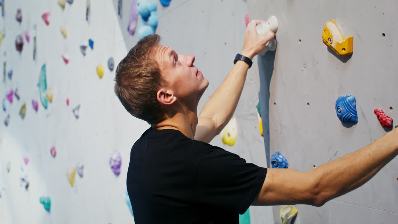 hombre escalando roca en la pared de escalada interior