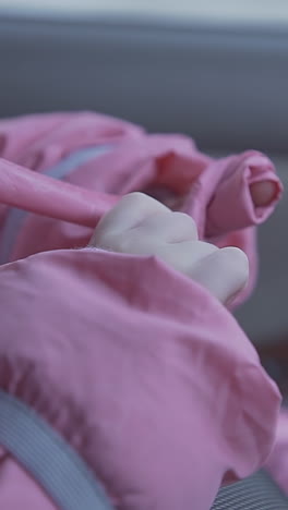 little girl in bright pink winter jacket sits in modern car salon with fastened seat belt extreme close view