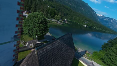 Torre-De-La-Iglesia-Con-Drones-Y-Puente-De-Piedra-Junto-Al-Lago-Bohinj-En-El-Pueblo-Alpino-De-Ribicev-Laz,-Eslovenia