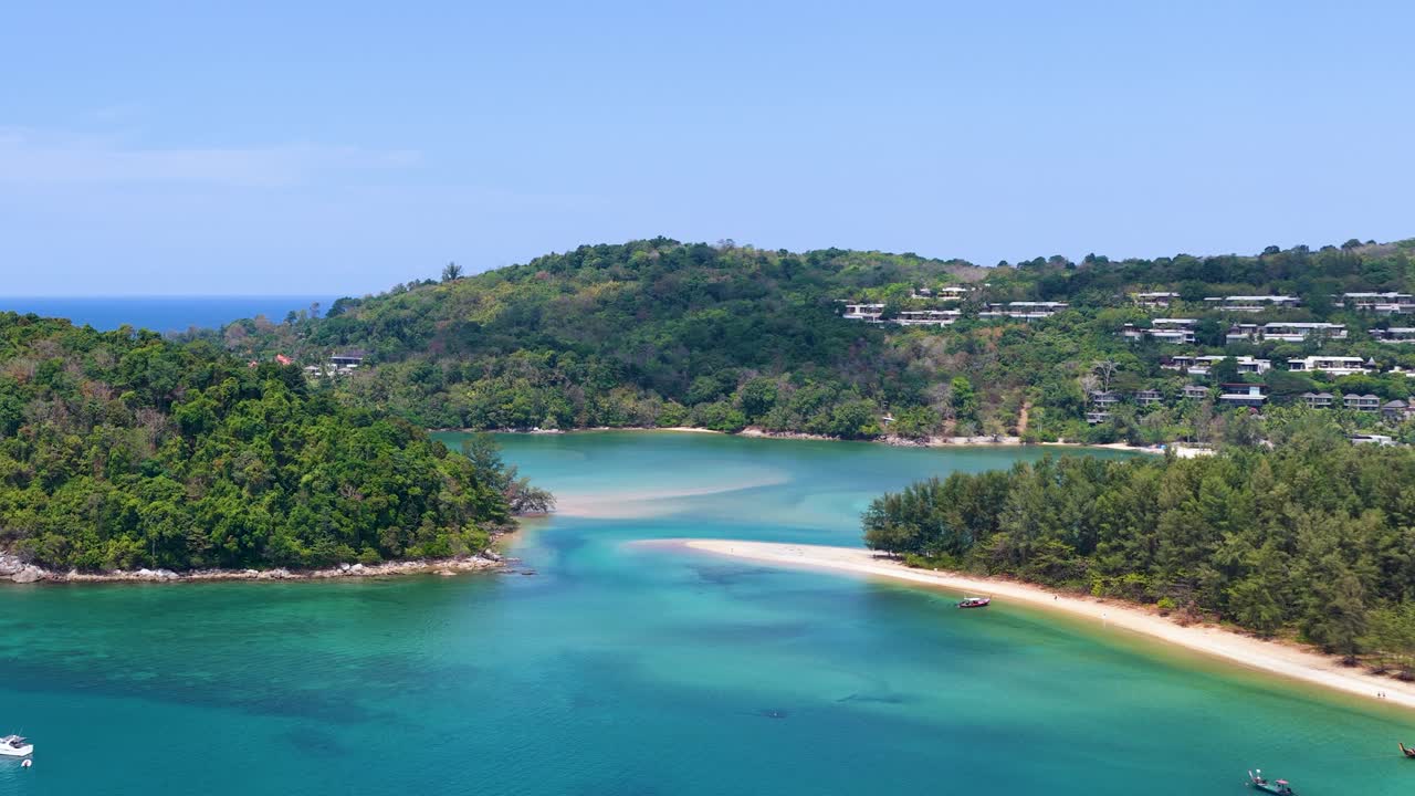 High angle drone shot of clear turquoise water and lush green islands under bright sunlight